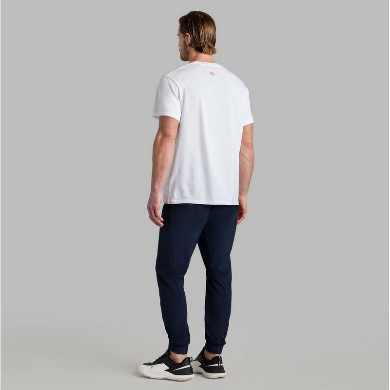 Man wearing a white t-shirt and navy pants on a gray background