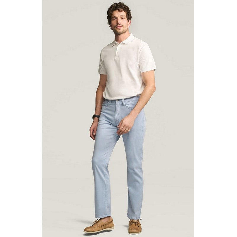 Man wearing a white polo shirt and light blue jeans against a plain background