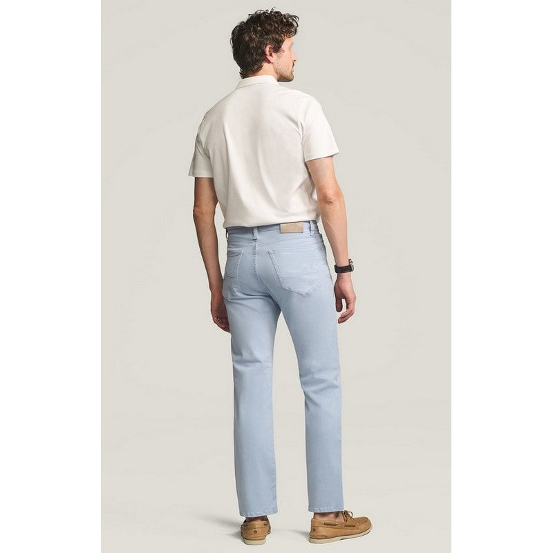 Man wearing light blue jeans and a white shirt on a plain background