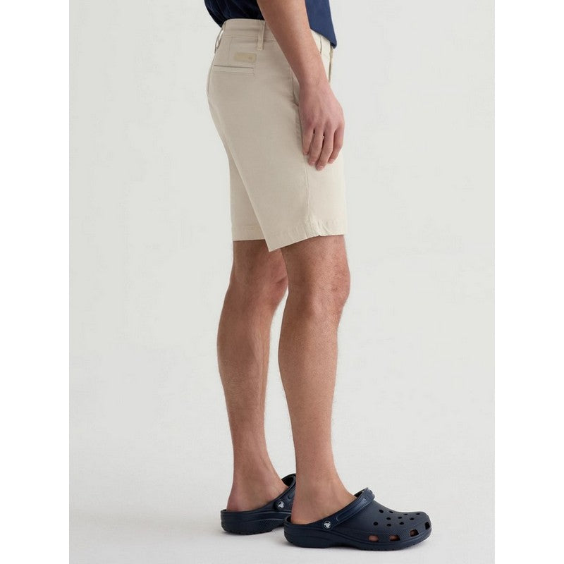 Person wearing beige shorts and navy Crocs on a white background