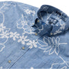 Blue denim shirt with white floral patterns and a brand label on a white background
