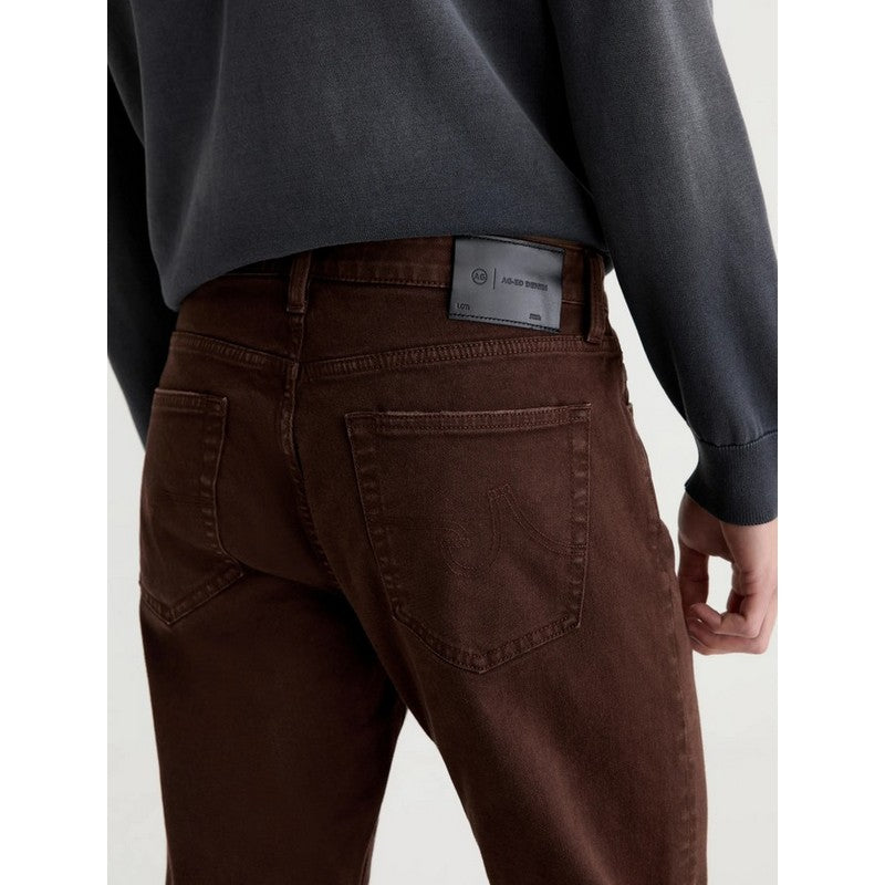 Rear view of a person wearing dark brown denim jeans and a dark charcoal sweatshirt, showing the back pocket and waistband label.
