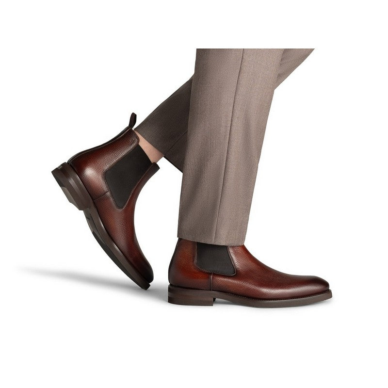 Brown leather shoes with black accents worn with beige pants on a white background
