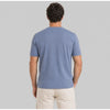 Man wearing a blue t-shirt and beige pants on a gray background