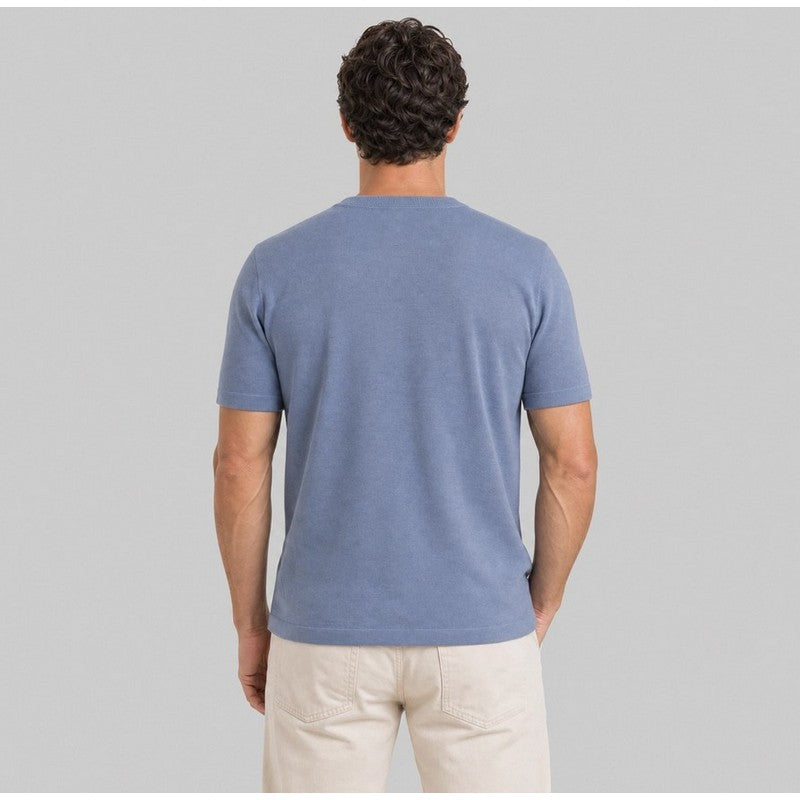 Man wearing a blue t-shirt and beige pants on a gray background