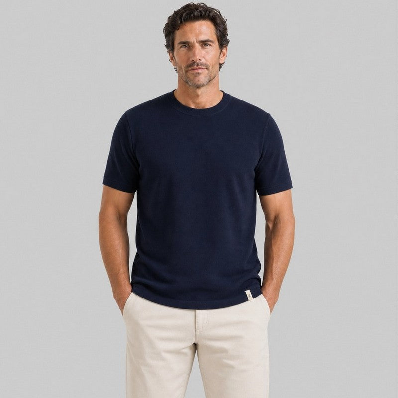 Man wearing a navy blue t-shirt and beige pants on a gray background
