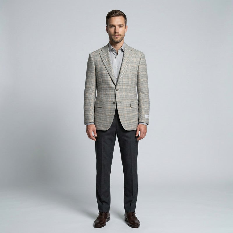 Man wearing a gray checkered blazer and dark pants on a light gray background