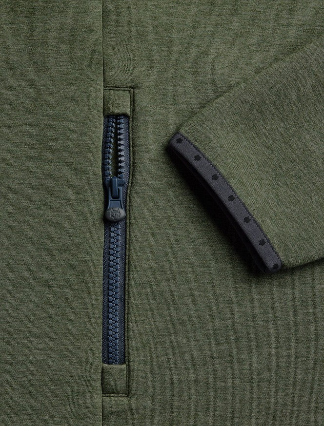 Close-up of an olive green knit garment showing a dark navy zipper and a matching navy sleeve cuff with small decorative dots.