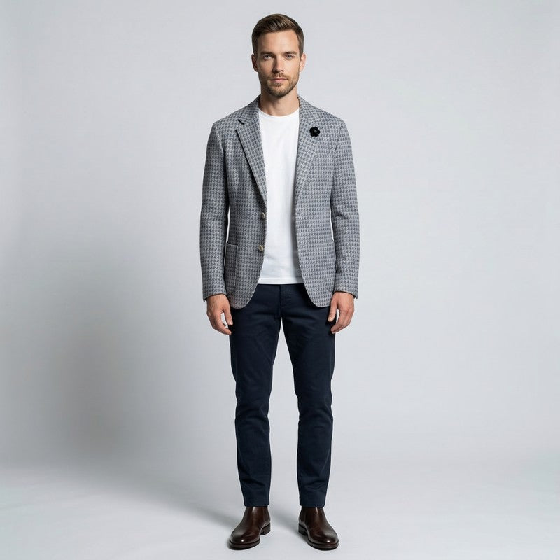 Man wearing a checkered blazer, white shirt, and dark pants on a light gray background