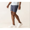 Person wearing blue shorts and white sneakers on a plain background