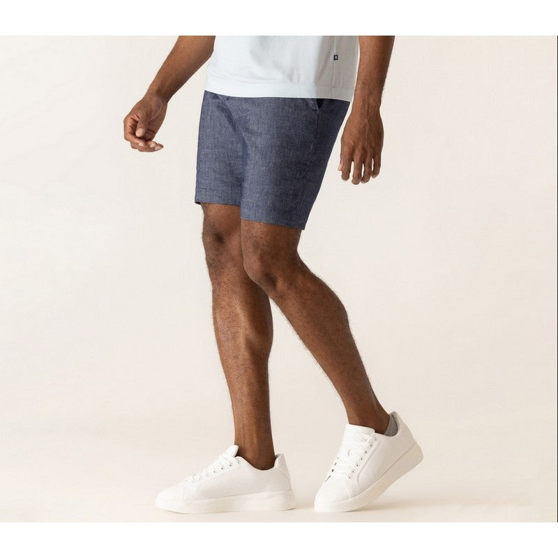 Person wearing blue shorts and white sneakers on a plain background