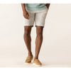 Person wearing light-colored shorts and tan shoes on a plain background