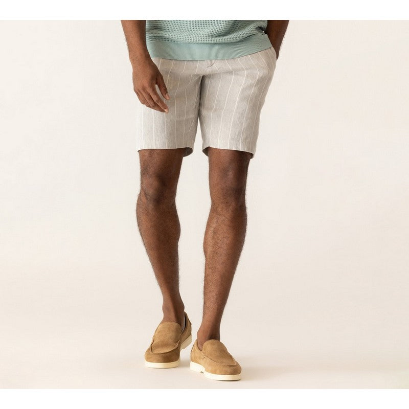 Person wearing light-colored shorts and tan shoes on a plain background