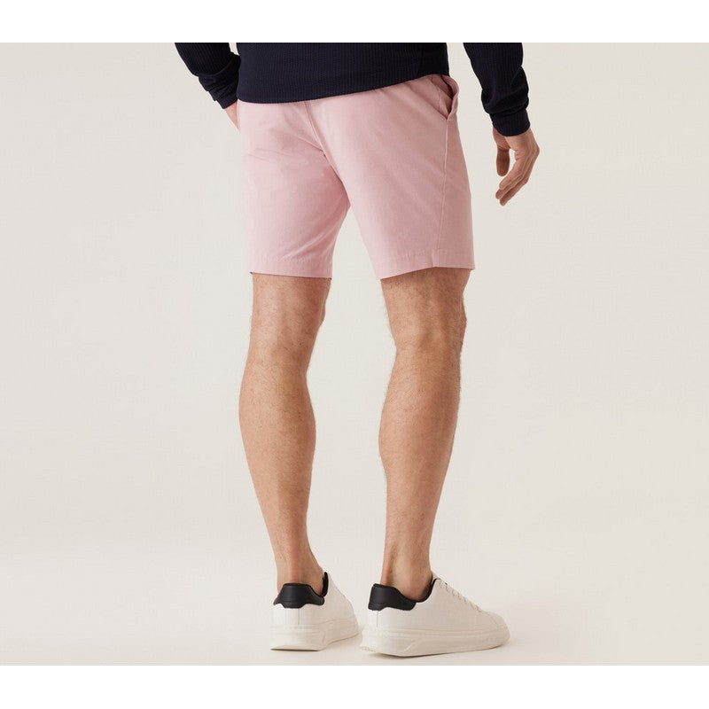 Person wearing pink shorts and white sneakers on a plain background