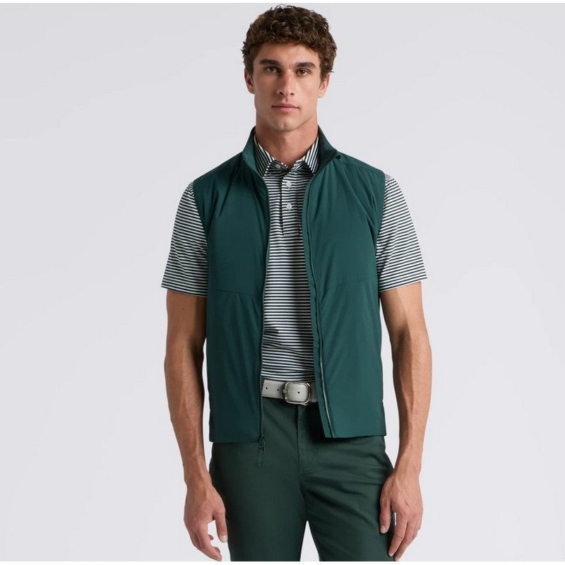 A man modeling a dark green sleeveless zip-front vest over a black and white striped polo shirt, paired with matching dark green trousers, against a light gray studio background.