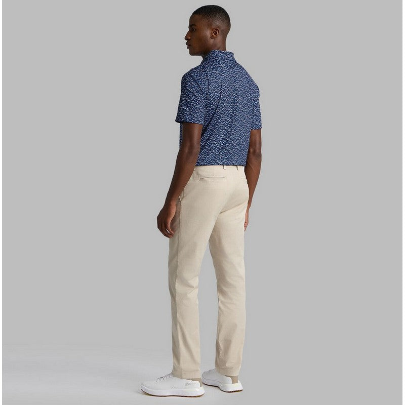 Man wearing a blue patterned polo shirt and beige pants on a gray background