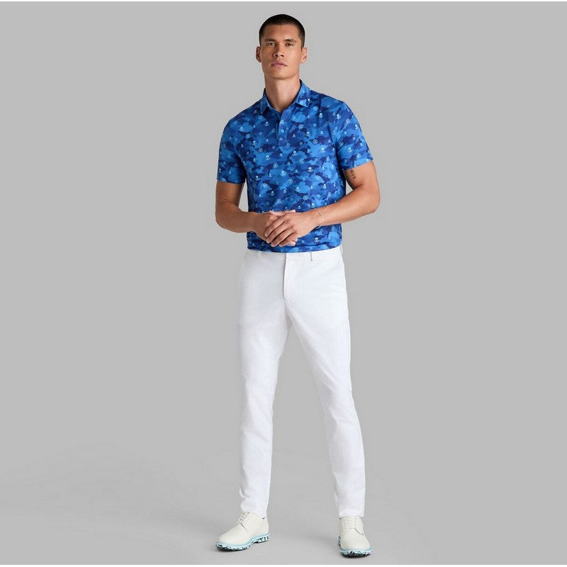 Man wearing a blue patterned shirt and white pants on a gray background