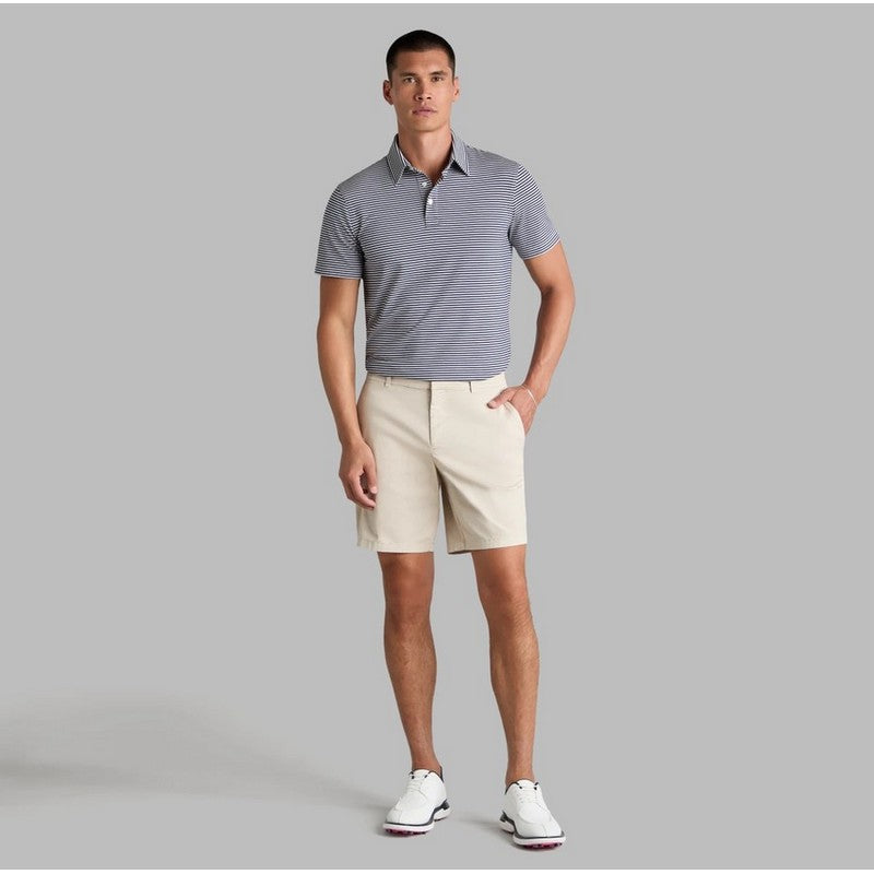 A man modeling a short-sleeve polo shirt with fine horizontal gray and white stripes, paired with beige shorts and white golf shoes, against a solid gray studio background.