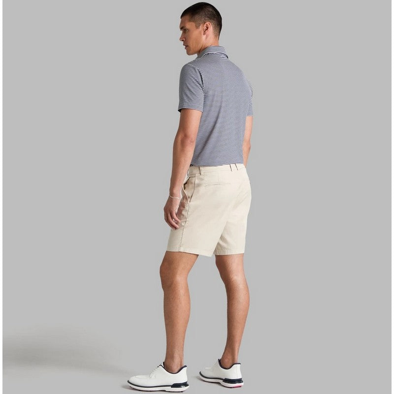 A man shown from the back wearing a gray and white striped polo shirt, beige shorts, and white golf shoes, standing against a solid gray studio background.