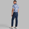 Man wearing a blue and white floral shirt with navy pants on a gray background
