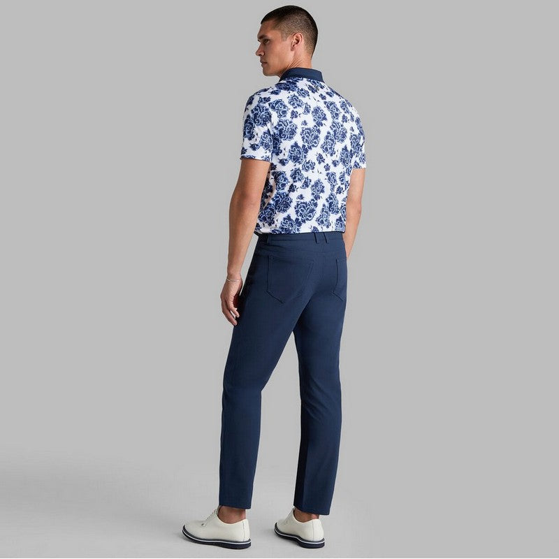 Man wearing a blue and white floral shirt with navy pants on a gray background