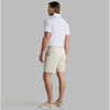 Man wearing a white polo shirt and beige shorts on a gray background