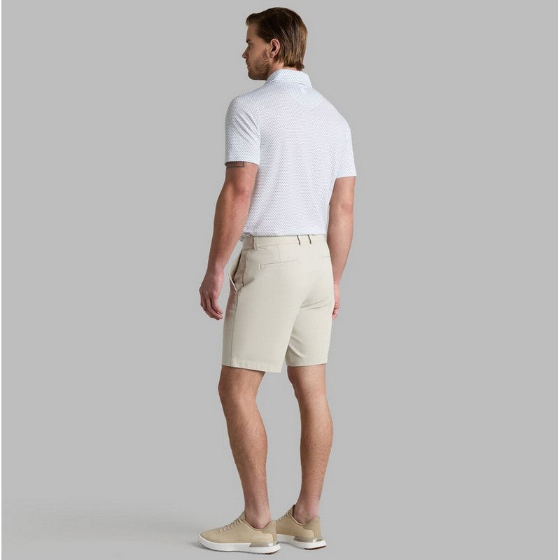 Man wearing a white polo shirt and beige shorts on a gray background