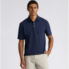 A man wearing a navy blue short-sleeve polo shirt with a chest pocket, paired with light beige trousers, standing against a light gray studio background.