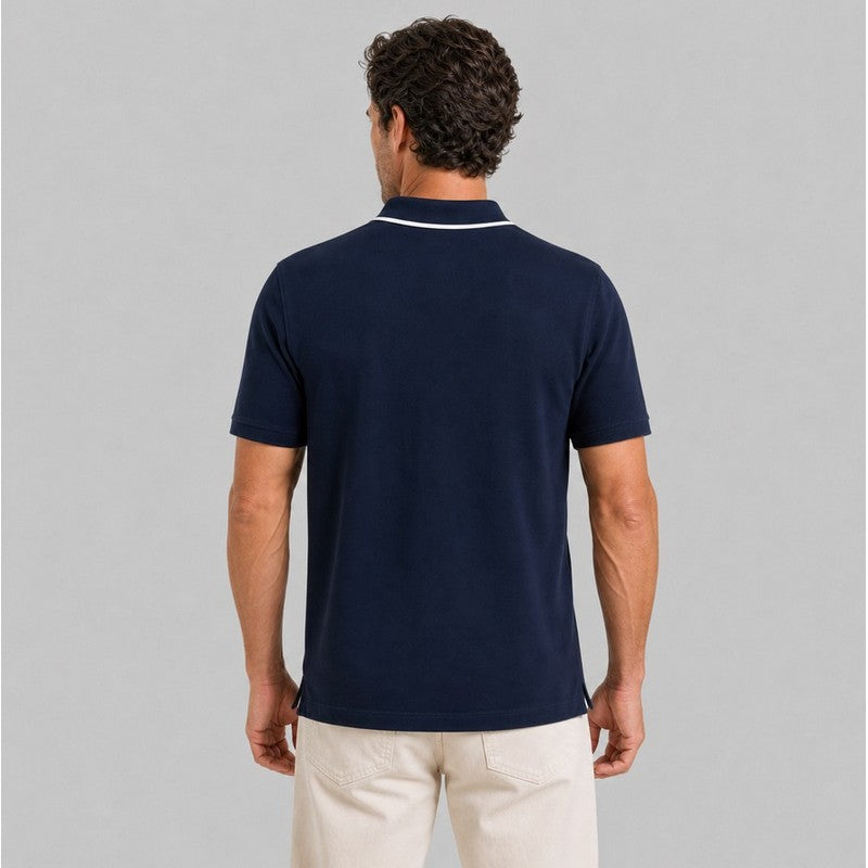 Man wearing a navy blue polo shirt on a gray background