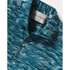 Close-up of a Tori Richard short-sleeve button-up shirt with a teal blue and white abstract pattern, featuring a visible brand label inside the collar.