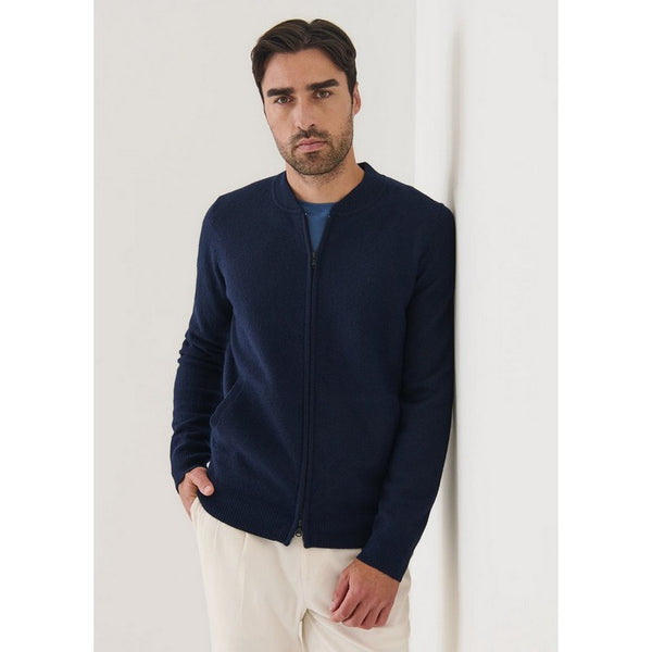 Man wearing a navy blue zip-up sweater against a white background