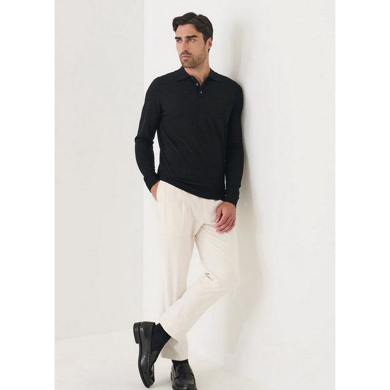 Man wearing a black long-sleeve shirt and white pants against a white background