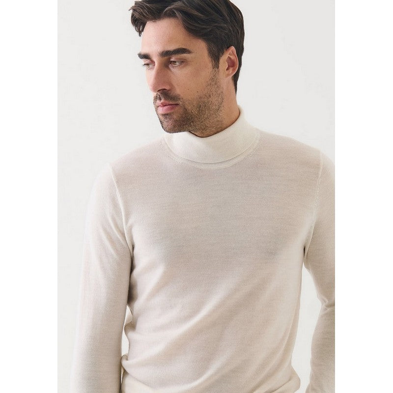 Man wearing a beige turtleneck sweater against a white background