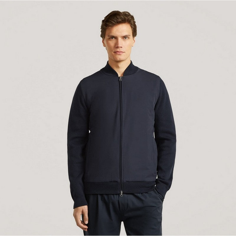 Man wearing a navy blue tracksuit on a light gray background