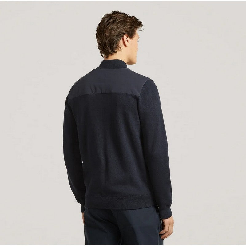 Man wearing a dark blue pullover with a plain background