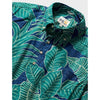 A close-up of a men's button-down shirt with a bold tropical leaf pattern in teal green and dark blue, featuring a pointed collar and visible brand label.