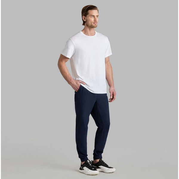 Man wearing a white t-shirt and navy pants on a gray background