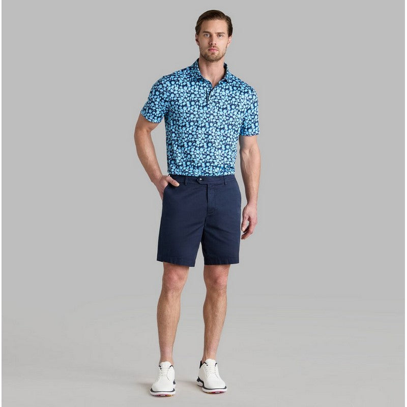 Man wearing a blue patterned polo shirt and navy shorts on a gray background