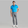 Man wearing a blue patterned polo shirt and gray pants on a gray background