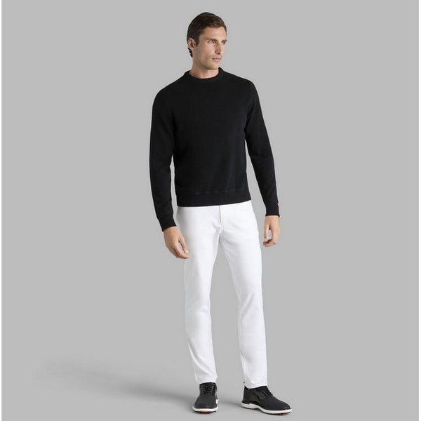 Man wearing a black sweater and white pants on a gray background