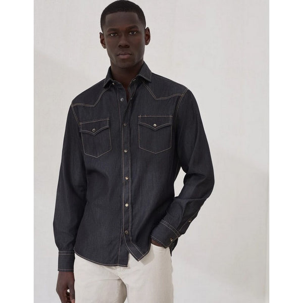 Man wearing a dark denim shirt with white pants on a plain background