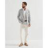 A man modeling a light gray pinstriped blazer, white dress shirt, off-white trousers, and tan loafers against a plain white studio background.