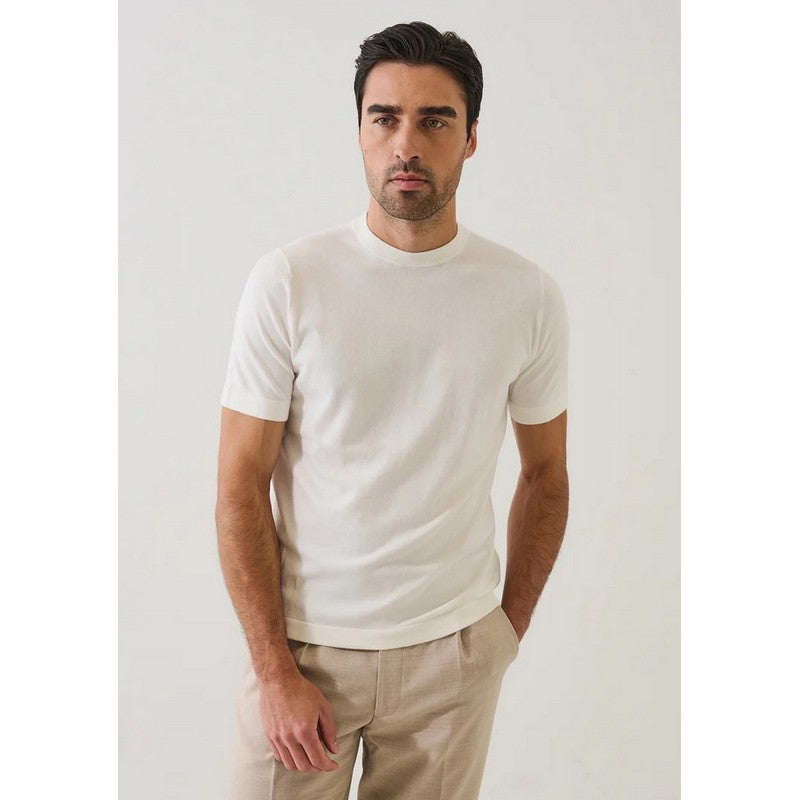 Man wearing a plain white t-shirt and beige pants against a light gray background