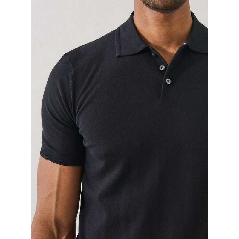 Black polo shirt worn by a person on a plain background