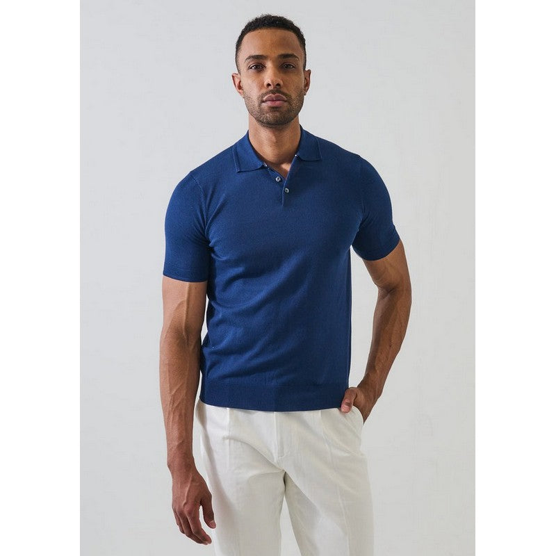 Man wearing a blue polo shirt and white pants against a light gray background