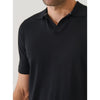 Black polo shirt worn by a person on a light gray background